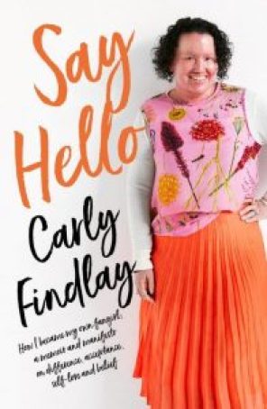 Book cover featuring woman with red face and short dark curly hair, smiling. She’s wearing a pink floral top and bright orange skirt. Her hand is on her hip. Curly orange text reads “Say Hello”, and black text reads “Carly Findlay How I became the fangirl of my own story - a memoir and manifesto on difference, acceptance, self love and belief.”