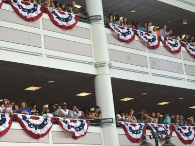Two floors with crowds overlooking the a large indoor space. People have their smartphones out. Patriotic bunting is hung on both floors.