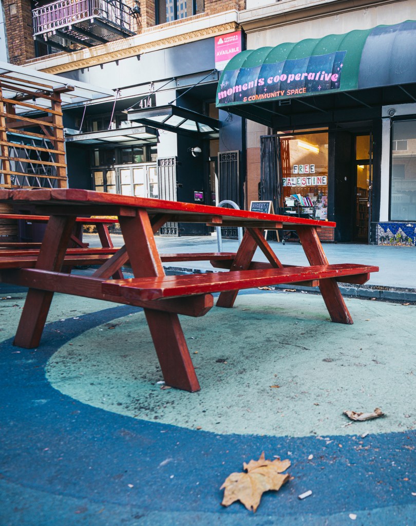 Red picnic tables in front of Moments, in a parklet on 13th Street. Photo by Brian Ringo, 2023.
