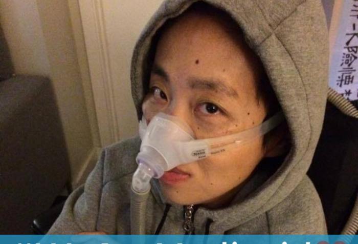 Image description: Asian American woman wearing a gray hoodie with her hands crossed across her chest. She is sitting in a wheelchair and had a BiPap mask over her nose with a tube. Below is a light blue horizontal bar with white text that reads: "#WeAreMedicaid." Next to the text on the right side is a graphic of a pink heart