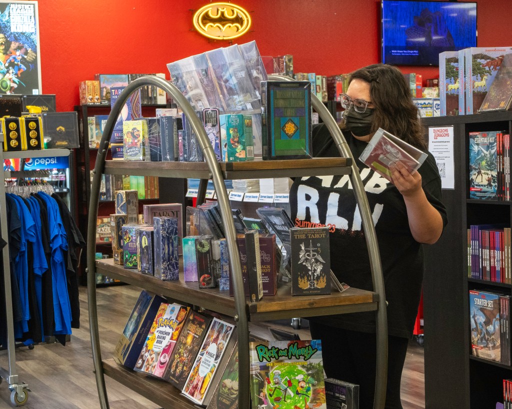 Illusive employee Danae wearing a KN95 mask while stocking merchandise. Photo by Brian Ringo, 2023.