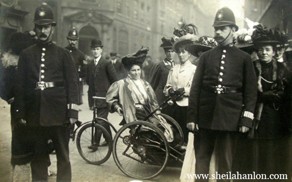 Black and white image of a woman reclining on a large tricycle that she uses due to her paralysis. She's surrounded by police officers.