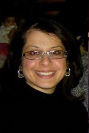 Photo of Dr. Rooshey Hasnain, a South Asian woman with should-length black hair. She is wearing eyeglasses and a black shirt. She is smiling at the camera.