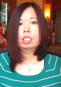 Photo of an Asian American woman with long straight hair. She is wearing a green sweater with white stripes and a necklace. 