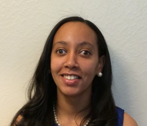 African American woman with long hair and wearing pearl earrings and a pearl necklace.