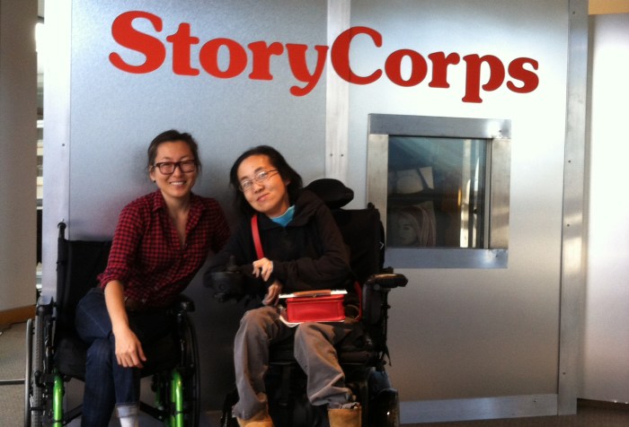 Two Asian American women in wheelchairs sitting in front of a StoryCorps recording booth