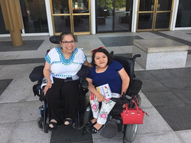 Image of Sandy Ho, a young Asian American woman in a wheelchair. On her left is Judy Heumann, an older white woman in a wheelchair.