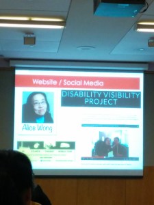 Image of a projection screen that features a screenshot of the Disability Visibility Project website. On the upper left hand corner is a photo of an Asian American woman in glasses.