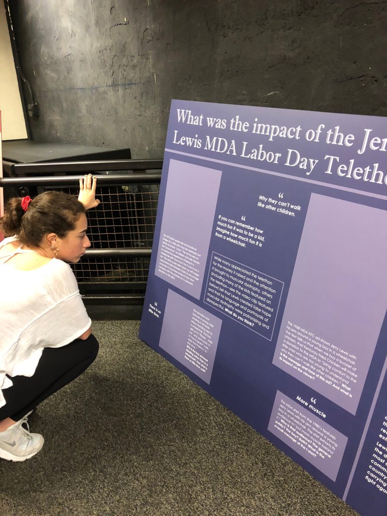 Student Skylar Kostinden proofreads a large wall panel for a museum exhibit with the title, “What was the impact of the Jerry Lewis MDA Labor Day Telethon?” Photo courtesy of Gann Academy. Photo credit: Maya Wainhaus