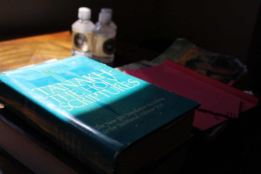 [A blue copy of “Tanakh: The Holy Scriptures” is partly covered in shadow.]