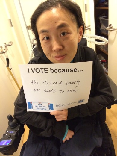 Image of an Asian American woman in a wheelchair holding a white piece of paper that says, "I Vote because...the Medicaid poverty trap needs to end."