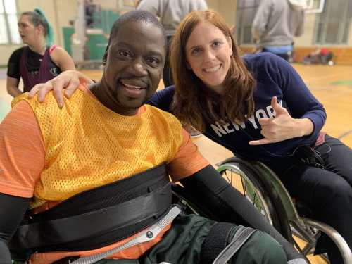 Photo of Daryl Chill Mitchell [left] a Black man in a chair designed for wheelchair rugby next to Katherine Beattie, a white woman in a manual wheelchair with her arm around his shoulder. Photo courtesy of Katherine Beattie.