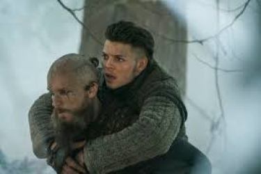 Image description: screenshot from an episode of Vikings, an original series on the History Channel. Ivar the Boneless is a young Viking warrior and he is being carried on the back of his friend and mentor Floki. The outdoor background is a snowy forest.