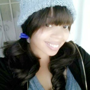 Image description: Woman, wearing a grey knit cap, smiling.