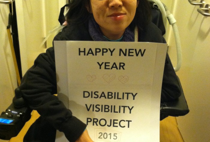 Image of an Asian-American woman in a wheelchair. She is holding a sign that reads: "HAPPY NEW YEAR" below that are 3 hearts and the text: "Disability Visibility Project 2015"