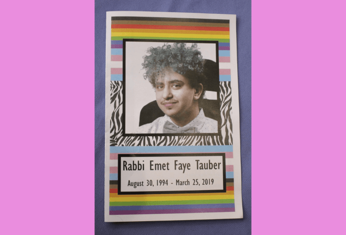 Graphic with a lavender background showing a photo of Emet’s funeral program. On the cover is a picture of Emet wearing a white and gray polka dotted collared button up shirt, with a gray bow tie. He has curly turquoise hair. He has a mustache and a nose piercing and is sitting in a power chair, smiling. Below it says Rabbi Emet Faye Tauber, August 30, 1994-March 25, 2019. In the background there are zebra stripes, rainbow pride flags, and trans pride flags.