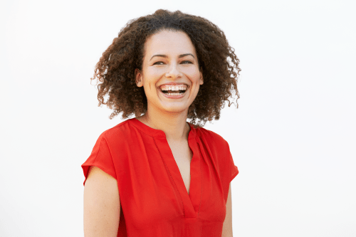 Headshot of Jen Brea, a young woman with curly brown hair with a wide smile. She is looking slightly away from the camera and wearing a short-sleeved red blouse.
