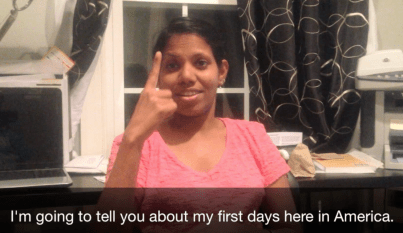 A South Asian woman in a pink shirt using sign language. A caption below the photo reads: "I'm going to tell you about my first days here in America."