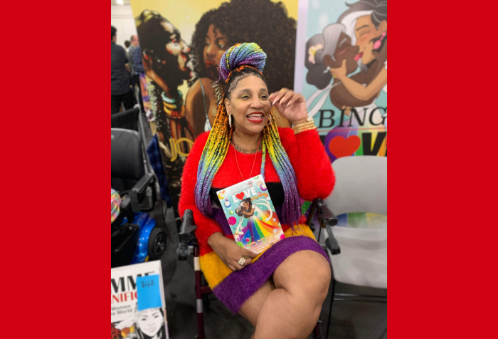 Graphic with a red background and a photo of Tee Franklin. Tee is attending a signing event for comic artists. She is sitting in a burgundy rollator walker, laughing as she holds a copy of her comic Bingo Love, on the cover is a drawing of two mature Black women embracing each other as they kiss, in skirts featuring the colours of the Pride flag. Tee is wearing a multicolored dress in a soft fuzzy texture. The colors are red, black, yellow, and purple. Tee’s hair is styled in traditional extension braids in colours to match her dress.
